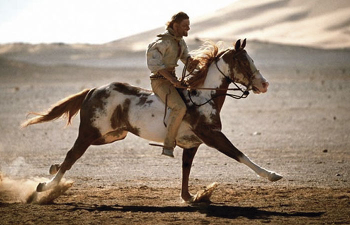 protagonista y su caballo galopando en su carrera por el desierto