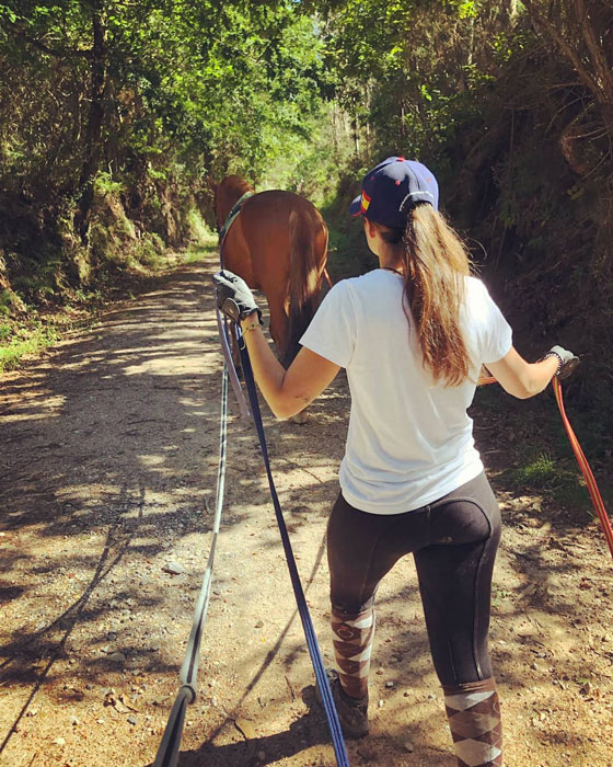 Marta Martínez, fisitaerapeuta y quropractica equina paseando un caballo añlazán por el campo con riendas largas